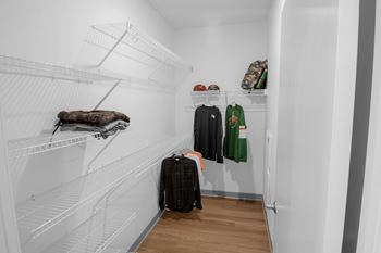 A white closet with clothes and shoes on shelves.